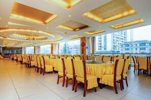 Un comedor amplio con varias mesas y sillas, ventanas grandes y un diseño moderno de techo.