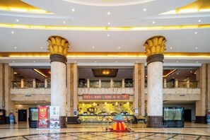A spacious lobby with a high ceiling, large columns, and a central decorative area.