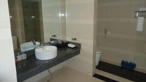 A bathroom with a white sink, a mirror, a shower, and a toilet. - Shengjing Hotel (Fuyuan)