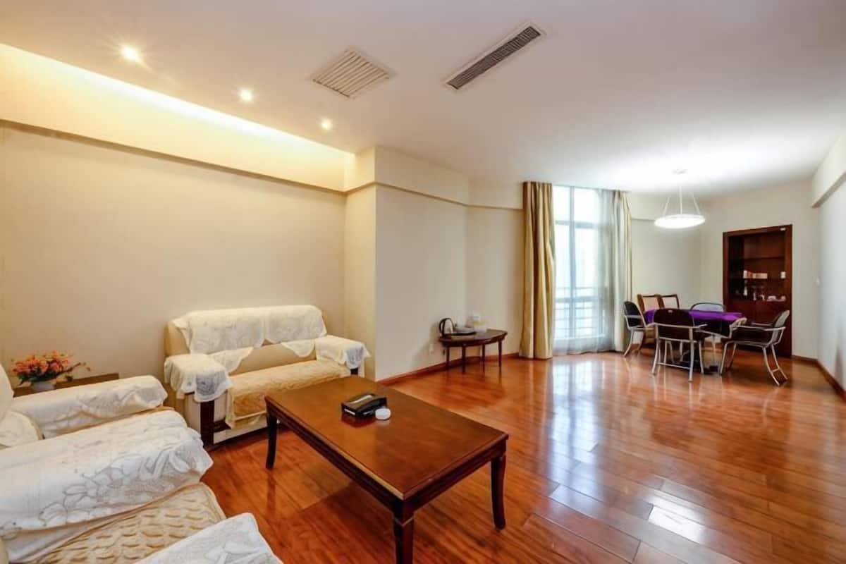 A spacious living area with a sofa set, a coffee table, and a dining table with chairs.