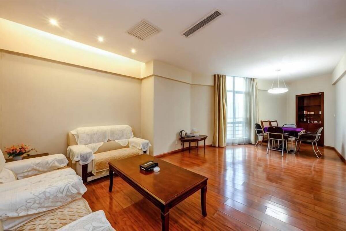 A spacious living area with a sofa set, a coffee table, and a dining table with chairs.
