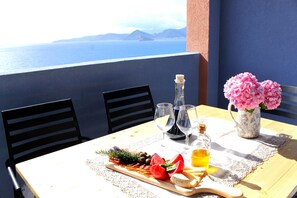 Un tavolo con un tagliere di salumi, calici di vino e un vaso di fiori.