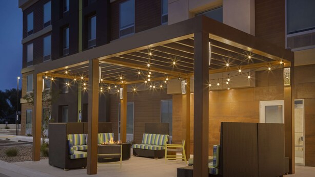 An outdoor patio area with seating and a fire feature, enclosed by a pergola with string lights. - Home2 Suites by Hilton Clovis (Clovis)