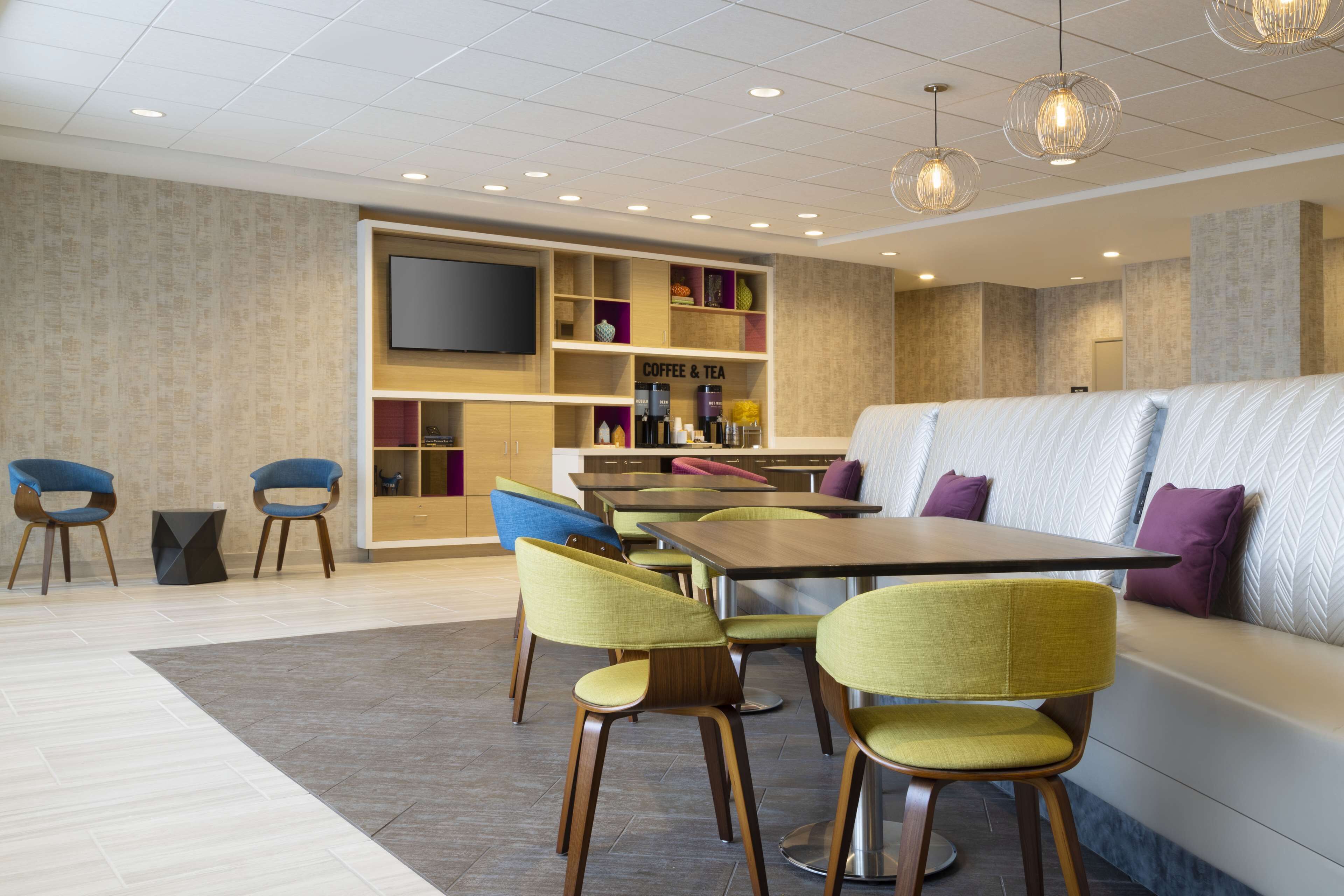 Um lobby de hotel moderno com área de estar, cantinho de café e chá e uma TV de tela plana.