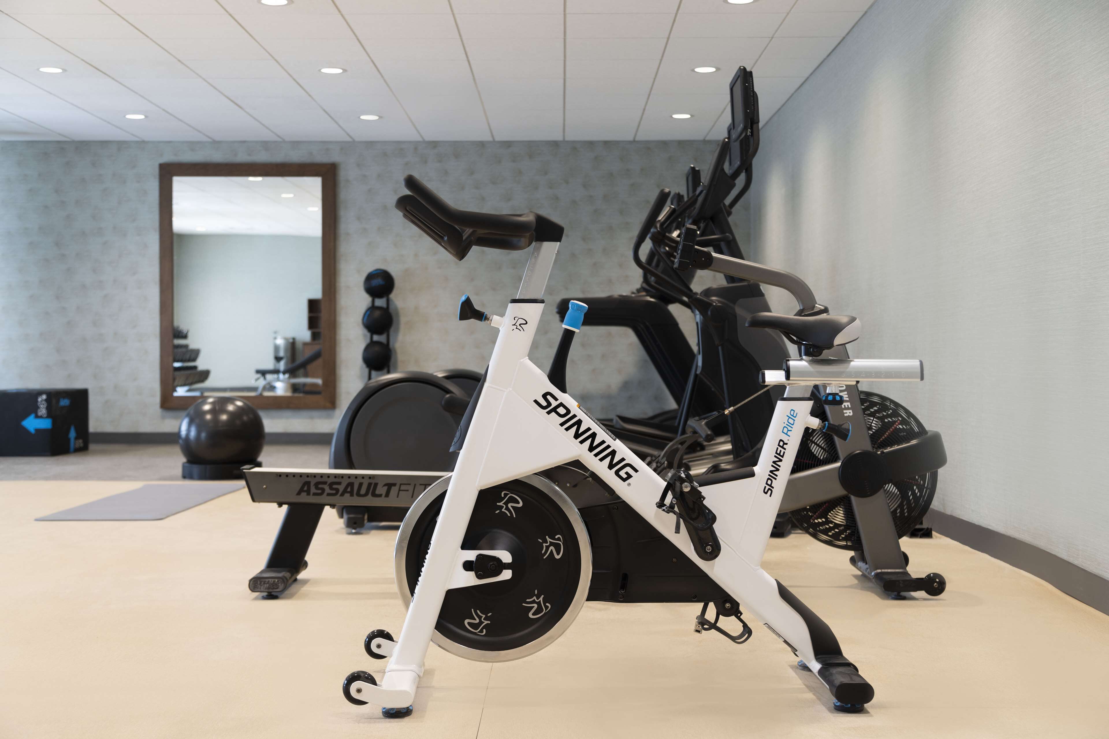 Ein Fitnessraum mit stationären Fahrrädern, Laufbändern und Trainingsbällen.