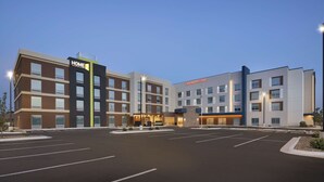 A modern hotel with a prominent 'HOME' sign, a 'Hampton Inn' sign, and a spacious parking lot. - Home2 Suites by Hilton Clovis (Clovis)
