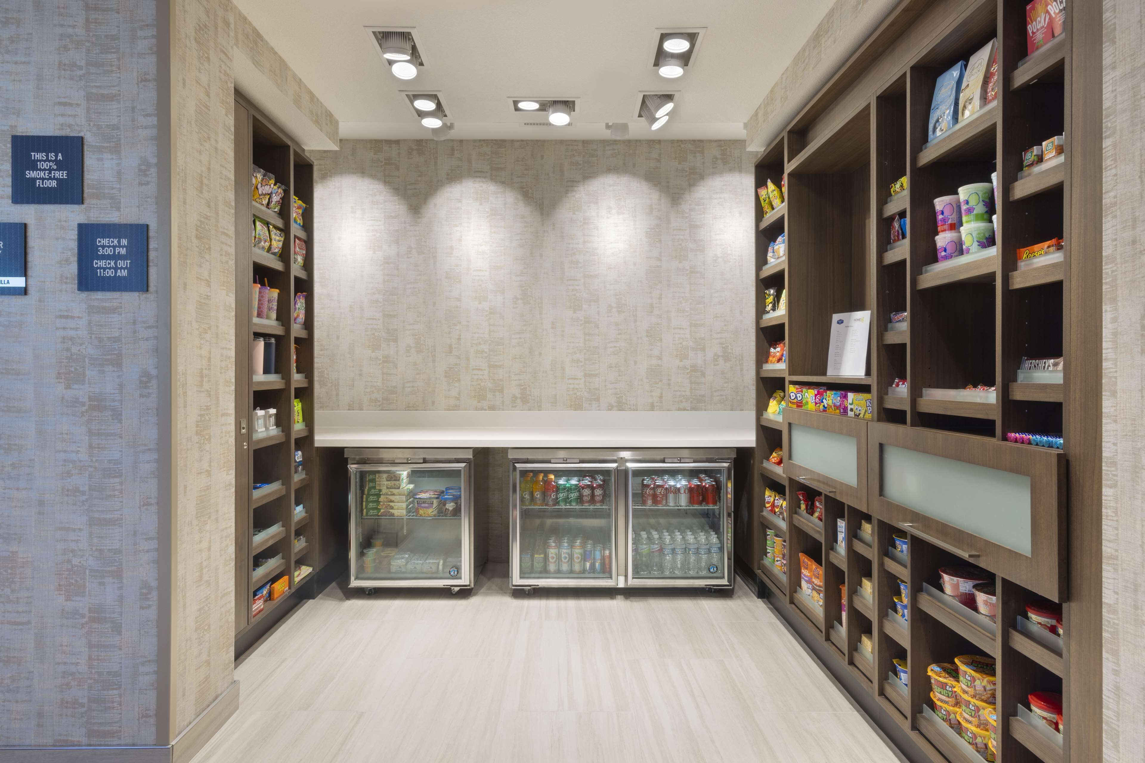Un bar de aperitivos limpio y bien iluminado, con bebidas refrigeradas y estantes llenos de productos.