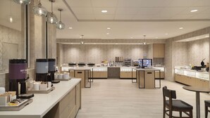 A modern hotel kitchen with multiple counters, coffee machines, and a seating area. - Home2 Suites by Hilton Clovis (Clovis)