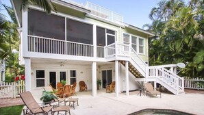 A two-story house with a covered patio, outdoor furniture, and a swimming pool. - All Seasons Villa (Captiva)