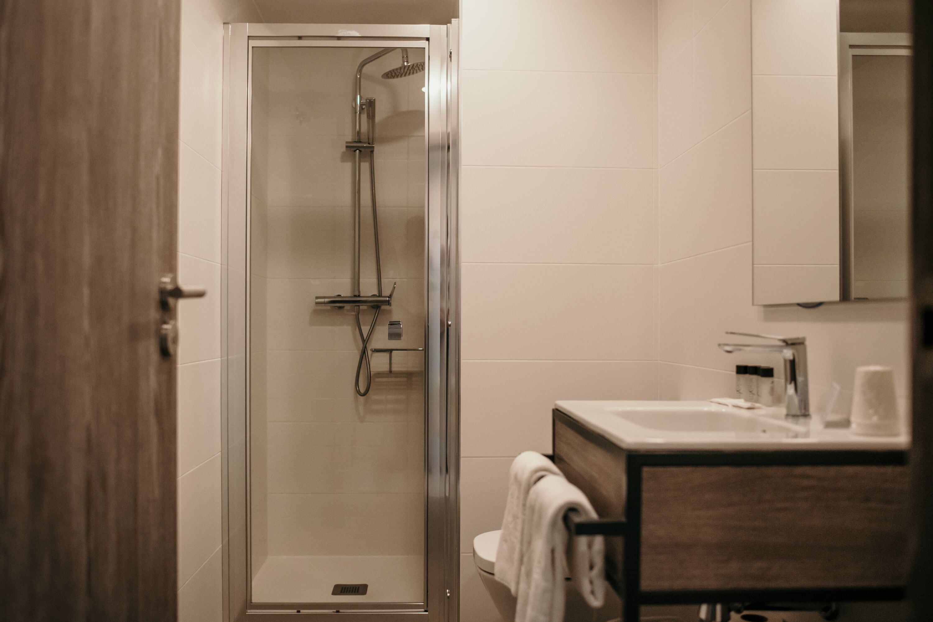 Une salle de bain moderne avec une douche à parois de verre, un meuble-lavabo en bois et un miroir au-dessus du meuble-lavabo.