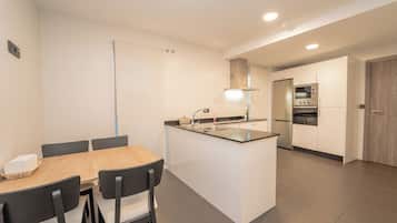 Une cuisine moderne dotée d’un îlot central, d’un coin repas avec une table et des chaises, ainsi que d’un four et d’un micro-ondes encastrés.