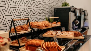 A buffet with various baked goods, including croissants and pastries, displayed on wooden boards. - Hotel Lux Melide (Melide)