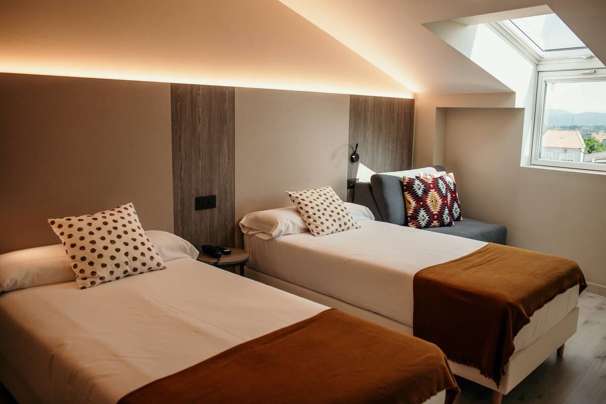 Ein Hotelzimmer mit zwei Betten, einem Oberlicht und Blick auf die Stadt.