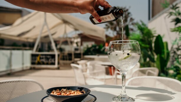 A person pouring a drink into a glass on an outdoor table. - Hotel Lux Melide (Melide)