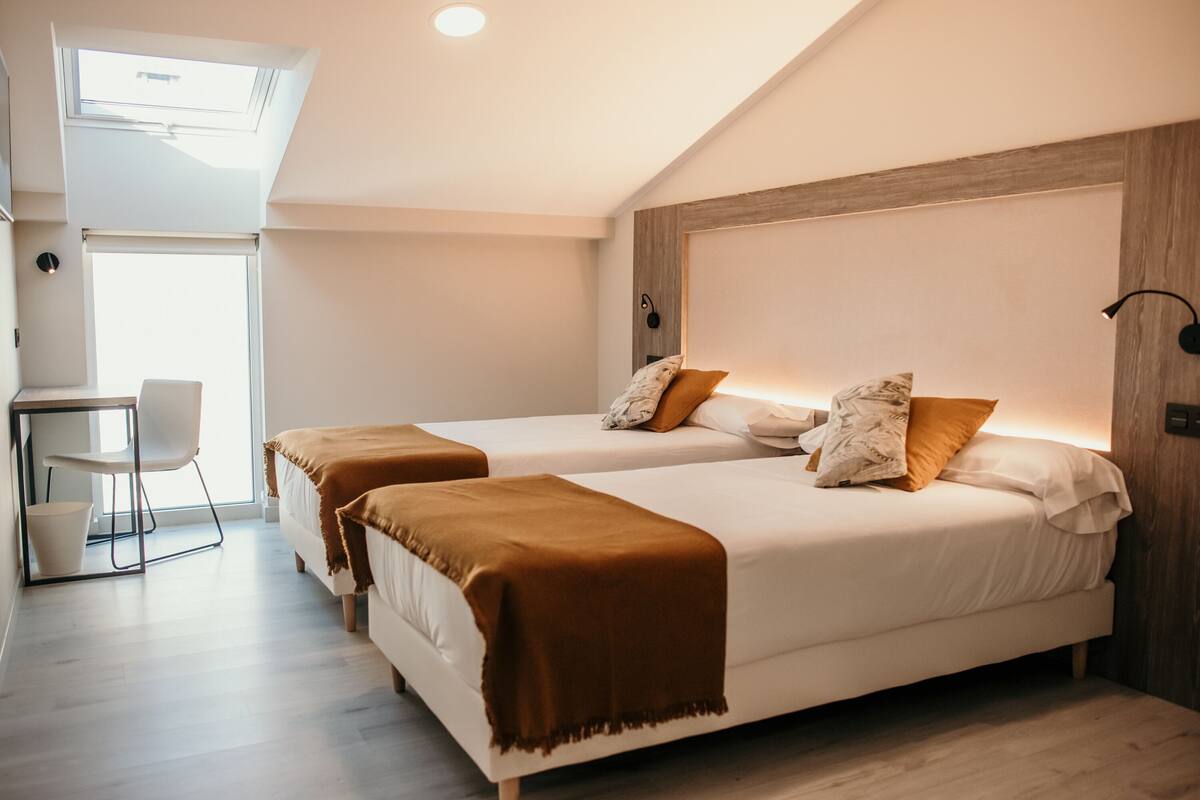 Ein modernes Schlafzimmer mit zwei Betten, einem Schreibtisch und einem Stuhl.
