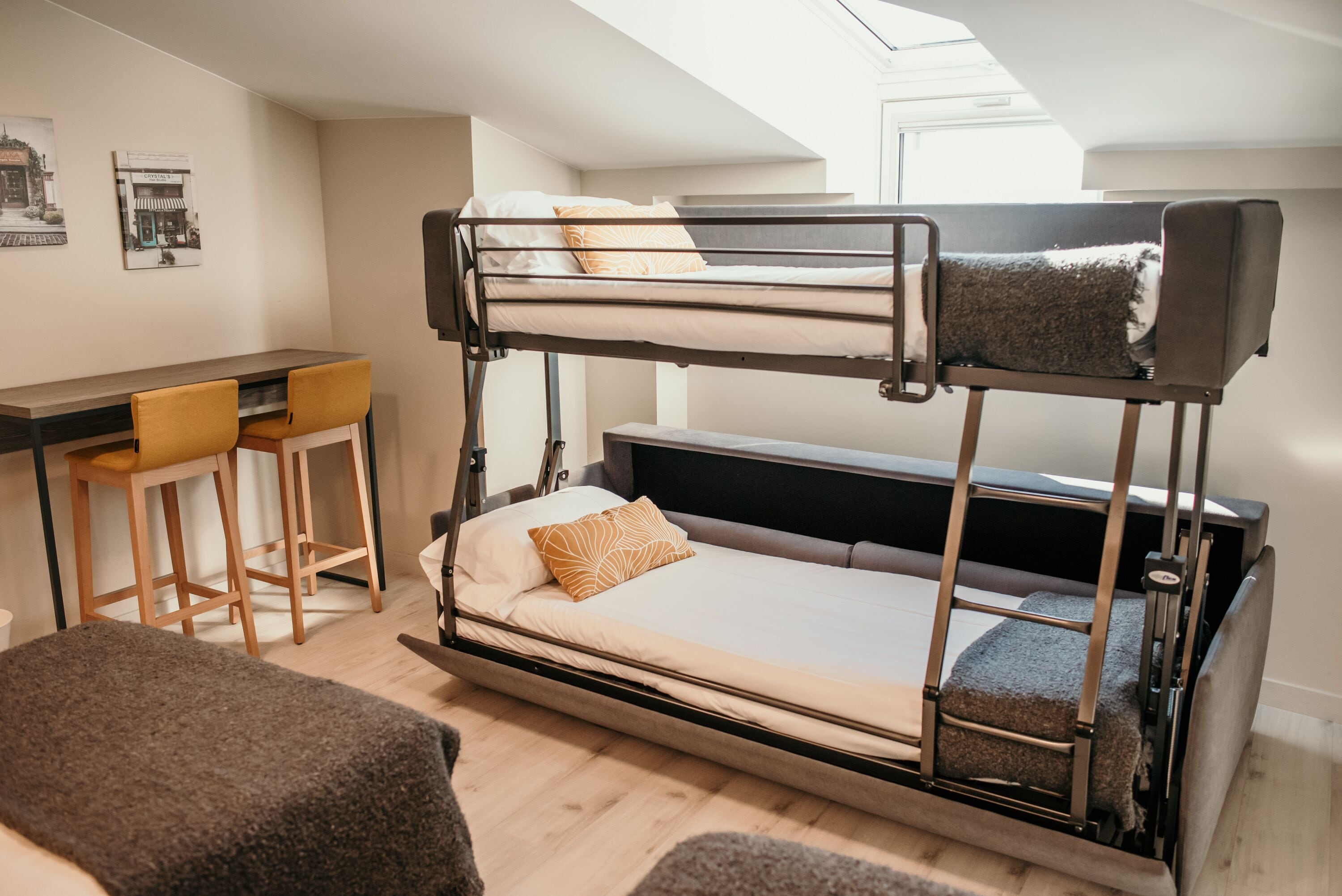 A bunk bed with a desk and two chairs, a small table, and a bench.