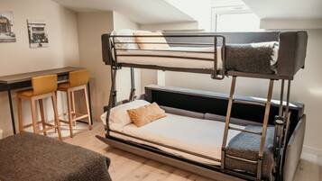 A bunk bed with a desk and two chairs, a small table, and a bench.