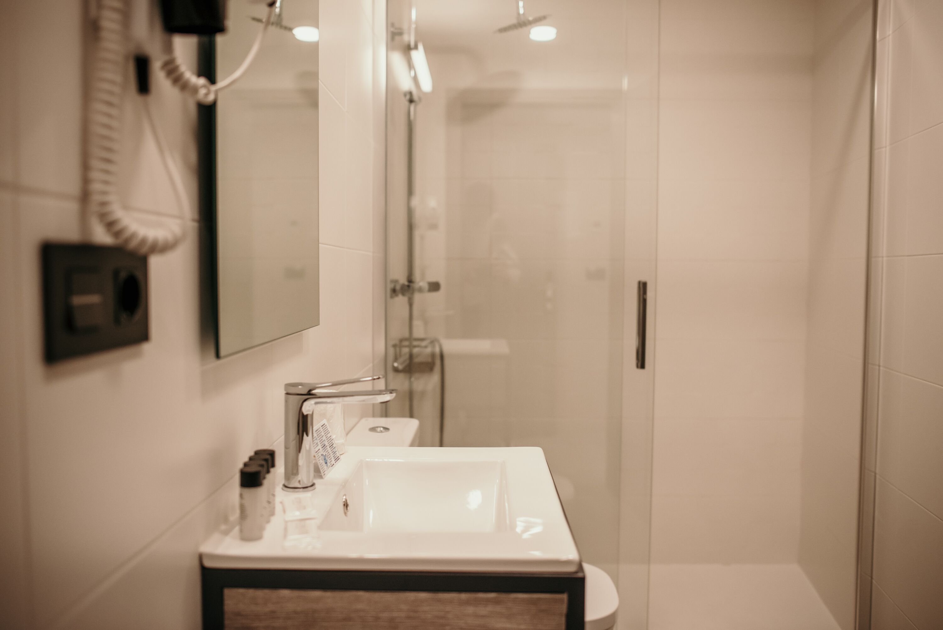 A modern bathroom with a glass shower enclosure, a white sink, and a mirror.