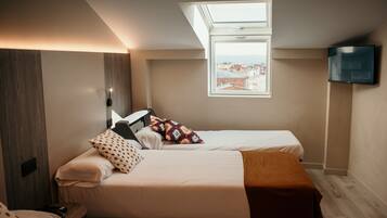 A bedroom with two beds, a skylight, a TV, and a city view.