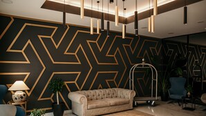 A modern lobby with a geometric patterned wall, a tufted sofa, and contemporary lighting fixtures. - Hotel Lux Melide (Melide)