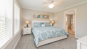 A bedroom with a bed, two nightstands, a ceiling fan, and a window with blinds.