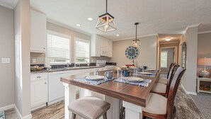 A modern kitchen with white cabinetry, a wooden island, and pendant lighting.