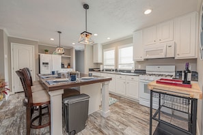 A modern kitchen with white cabinets, a wooden island, a stainless steel refrigerator, and a built-in oven. - Coastal Cottage 15 Minutes to Lewes Beach + Bike Trail Access. (Milton)