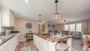 A spacious kitchen with a central island, white cabinetry, and a large clock on the wall.