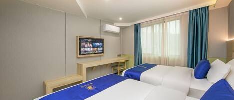A hotel room with two beds, a desk, a television, and a window with curtains.