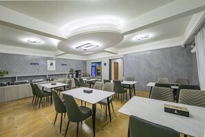 A dining area with tables and chairs, a kitchen area, and a counter. - Super 8 Selected Hotel (Fuzhou IKEA Shangyang Metro Station Branch) (Fuzhou)