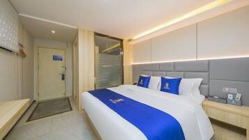 Quarto de hotel moderno com uma cama grande, mesa de cabeceira e painel de cabeceira embutido.