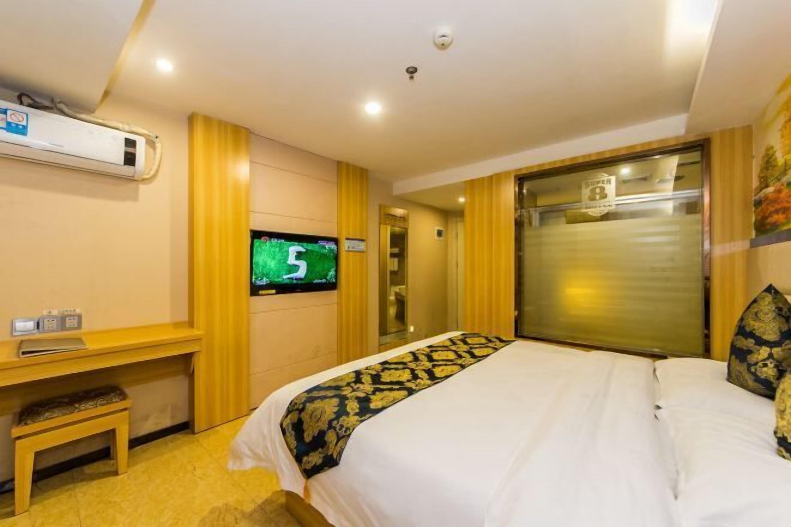 A hotel room with a bed, a desk, a television, and a sliding door.
