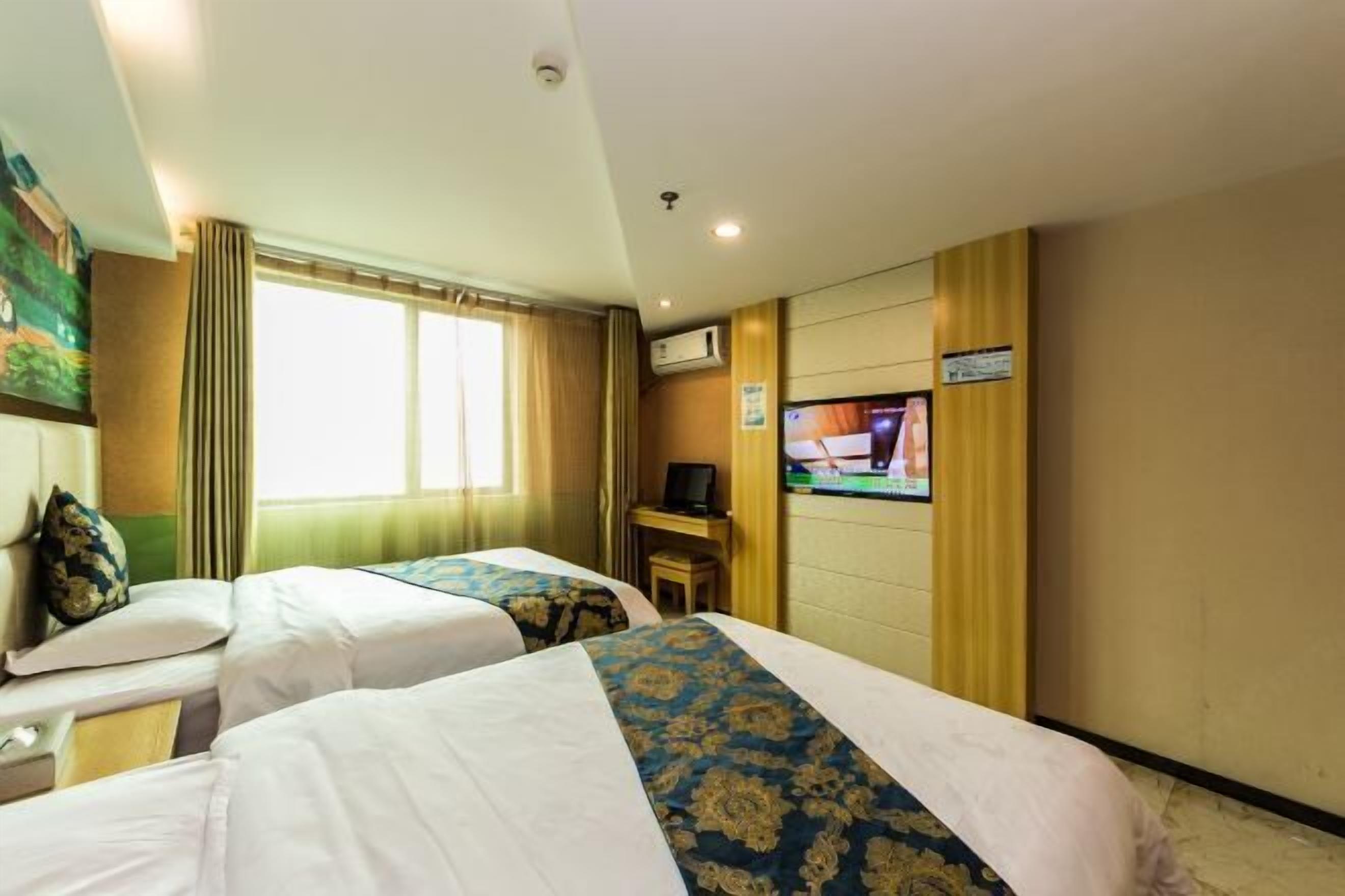 Ein Hotelzimmer mit zwei Betten, einem Fernseher und einem Fenster mit Vorhängen.