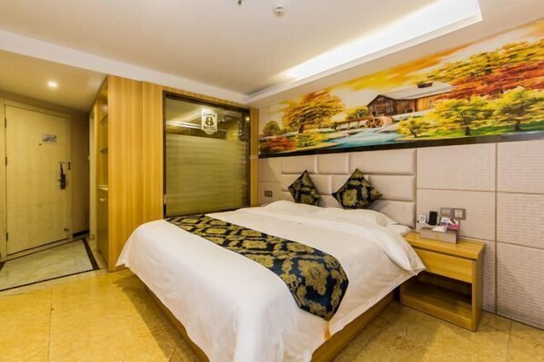 A hotel room with a bed, a nightstand, a painting on the wall, and a door.