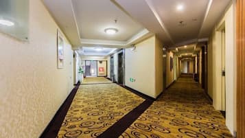 Passadís d'hotel amb un sòl de mosaic, il·luminació empotrada i portes d'accés a les habitacions.