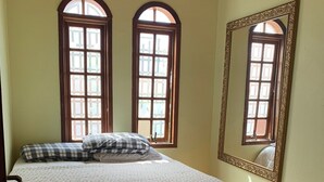 A bedroom with a bed, two arched windows, a mirror, and patterned tiles. - Paradise on the shores of Ibiraquera Lagoon (Imbituba)