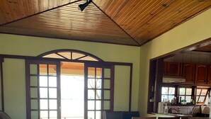 A spacious living area with a sofa, dining table, and chairs, a kitchen in the background, and a view through a large glass door. - Paradise on the shores of Ibiraquera Lagoon (Imbituba)