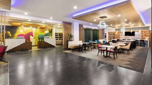 Eine moderne Hotellobby mit einer Rezeption, einer Sitzecke und einer Küche im Hintergrund.