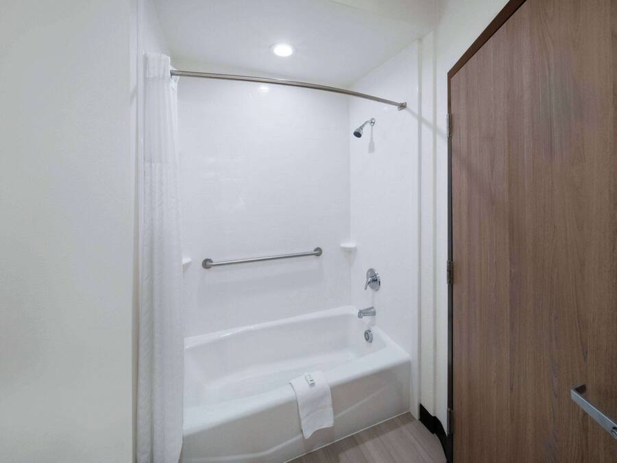 Ein modernes Badezimmer mit einer weißen Badewanne, einer Duschkabine und einer Holztür.