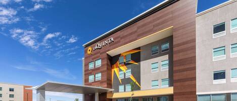 A modern hotel with a prominent La Quinta logo, a covered entrance, and a parking area with marked spaces.
