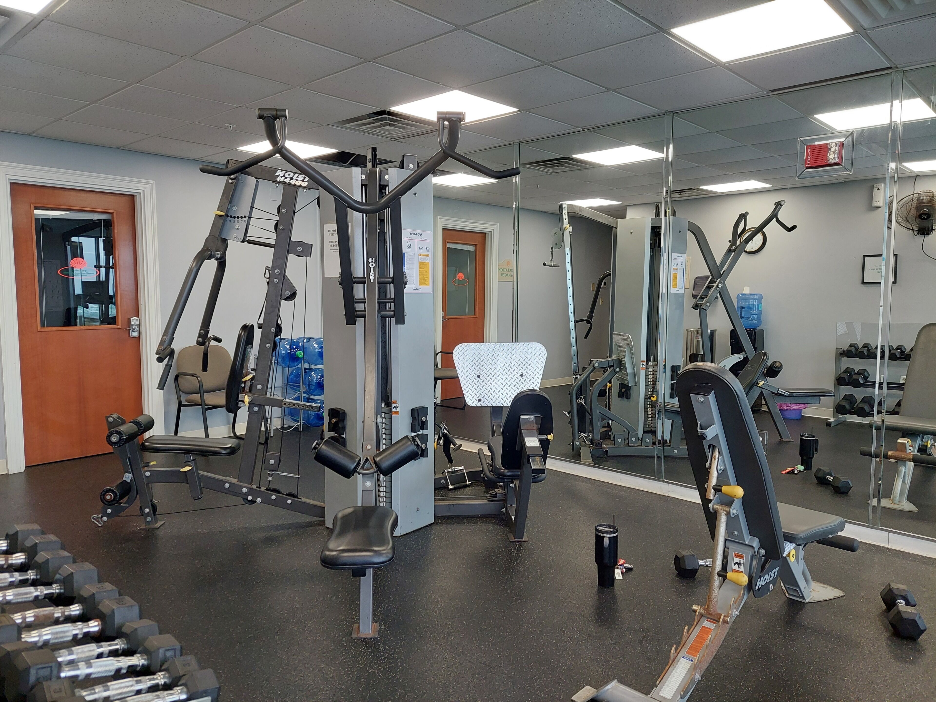 A gym with various exercise equipment, including weight machines, benches, and dumbbells.