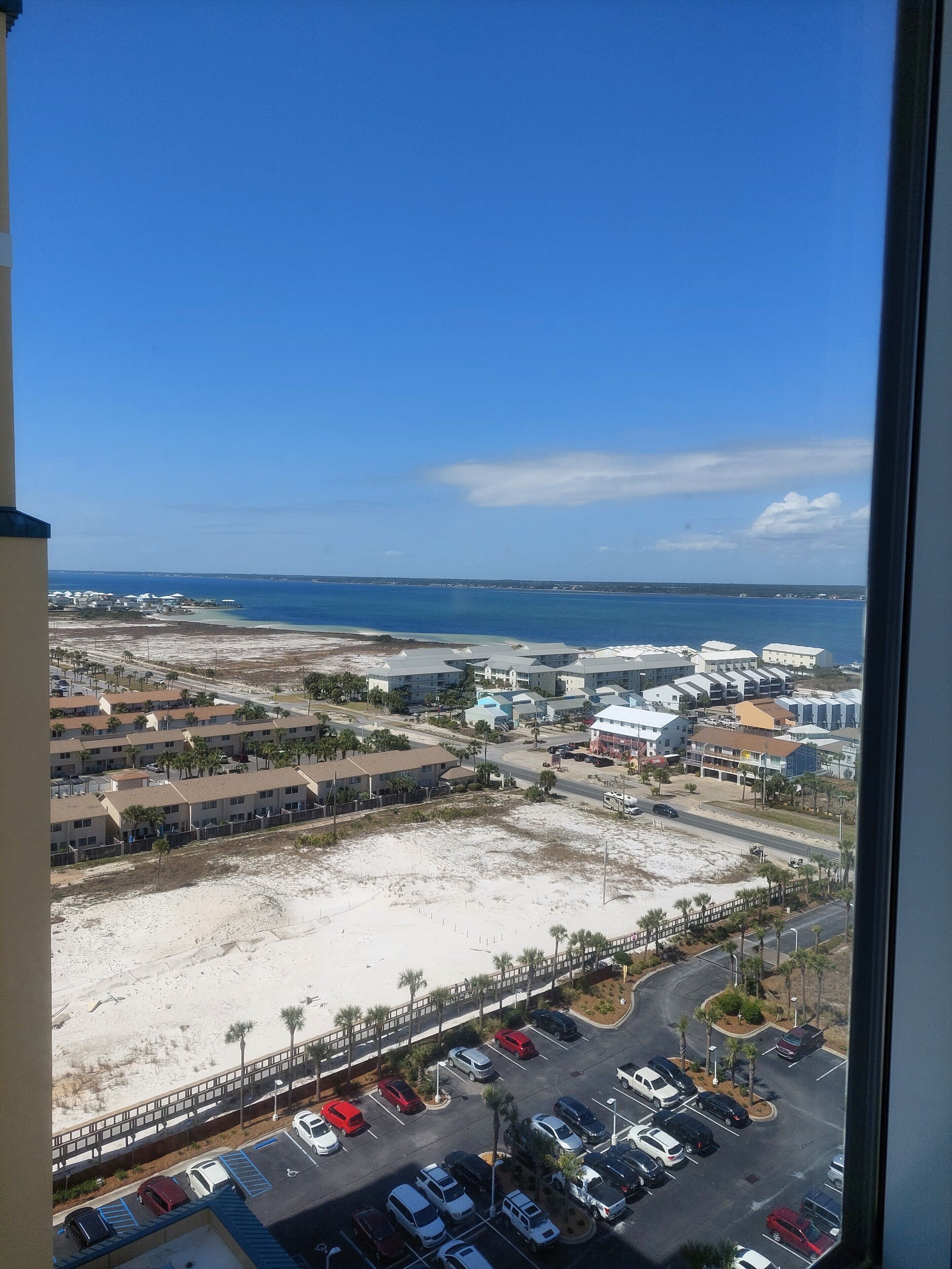 A coastal view with a parking lot, buildings, and a beach.