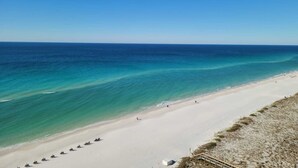 A beach with clear turquoise waters, a sandy shore, and a wooden walkway leading to the water. - Stunning Beach Views of Gulf-14th Floor-Dog friendly-See the longest pier in FL! (Navarre)