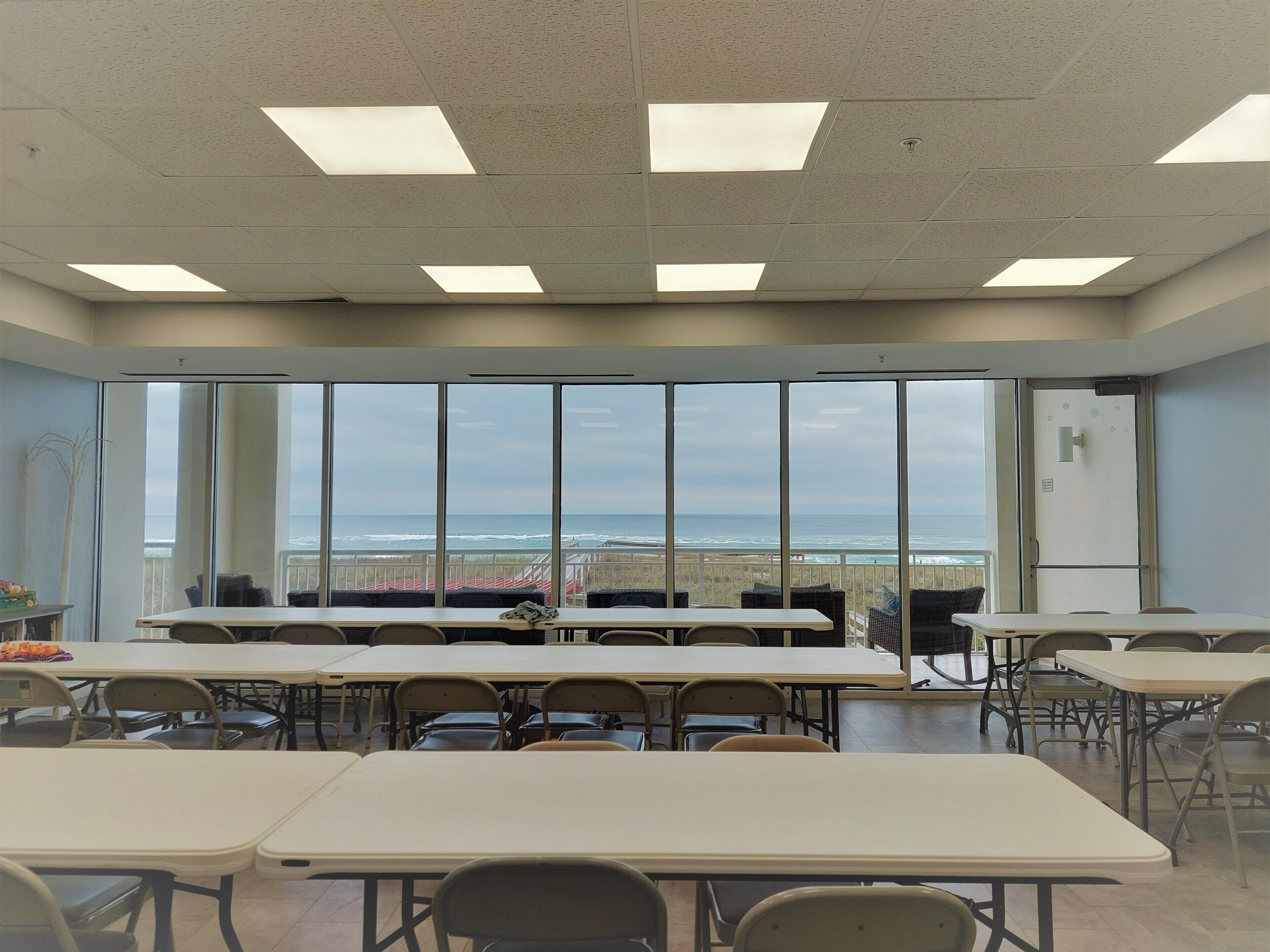 Un aula con amplios ventanales que dan al océano, equipada con mesas y sillas.