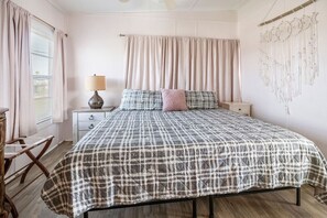 Une chambre à coucher avec une couvre-lit à carreaux, une lampe de chevet, une table de chevet et une décoration murale.