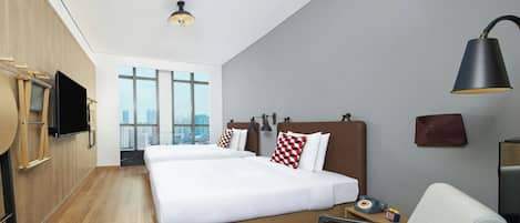 Una habitación de hotel moderna con una cama grande, un escritorio, una silla, un televisor y vistas a la ciudad.
