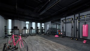 A gym with a stationary bike, treadmills, weight machines, and a punching bag. - Moxy Shanghai Xuhui (Shanghai)