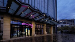 A modern building with a glass facade and a neon sign reading "mozy". - Moxy Shanghai Xuhui (Shanghai)