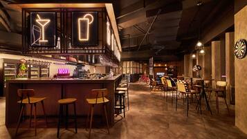 A bar area with stools, a bar counter, and a neon sign.