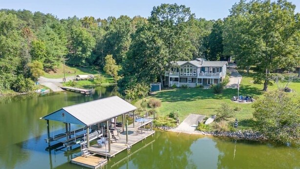 A lakeside property with a dock, a covered seating area, and a large house with a porch. - Lakefront Retreat with Game Room, Hot Tub, and Gym! (Goodview)